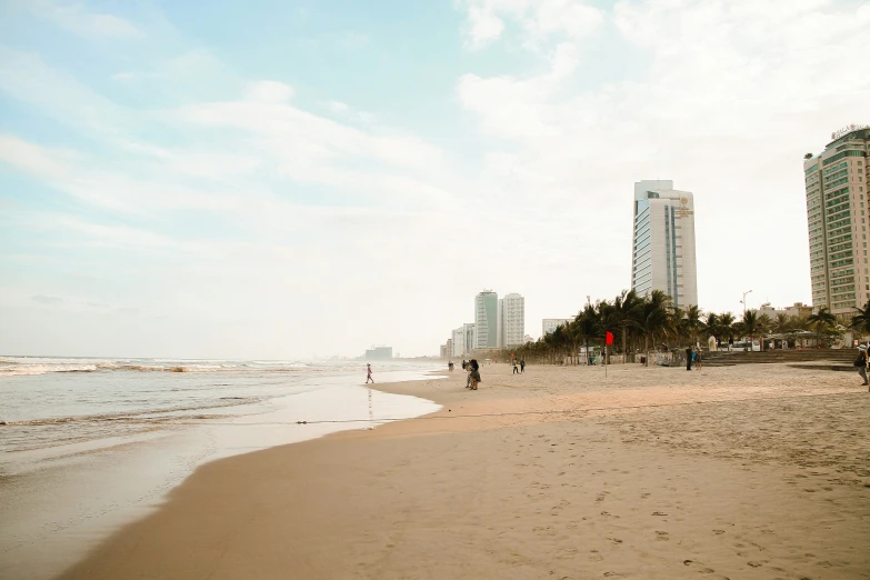 a man walking along the beach next to tall buildings