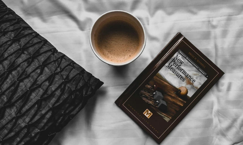 a white cup and book on a bed