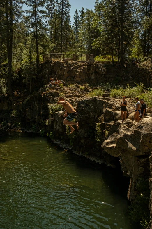 a man jumping into the water from some rocks