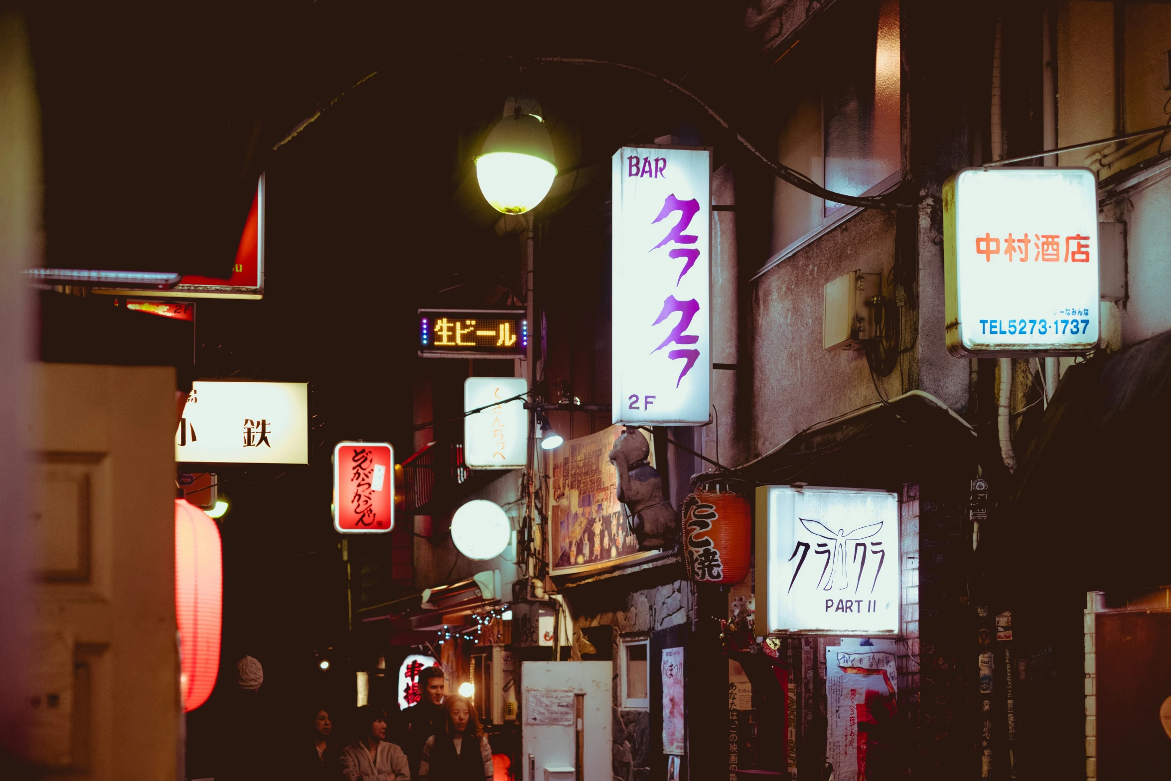 a dark alley that shows the light posts and neon signs