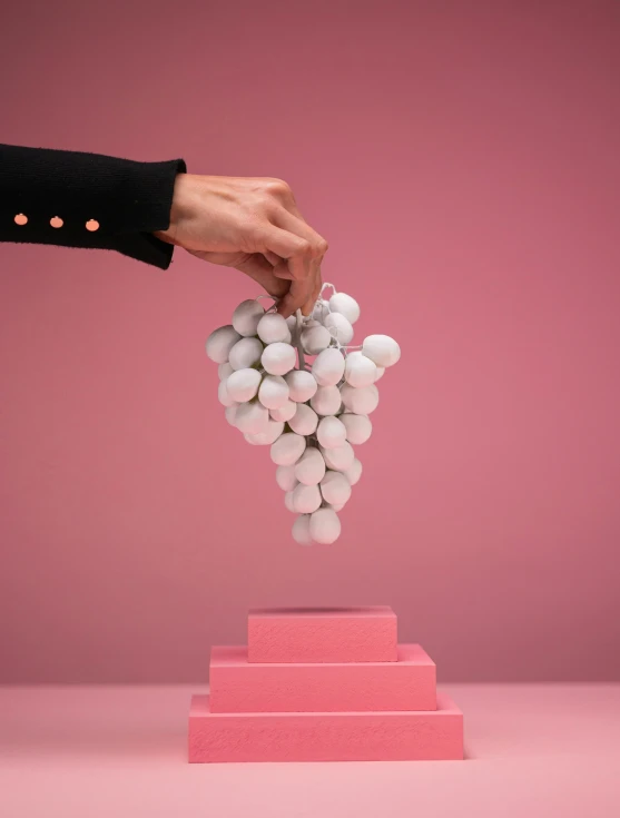 a person balancing a bunch of white balls on a pink structure