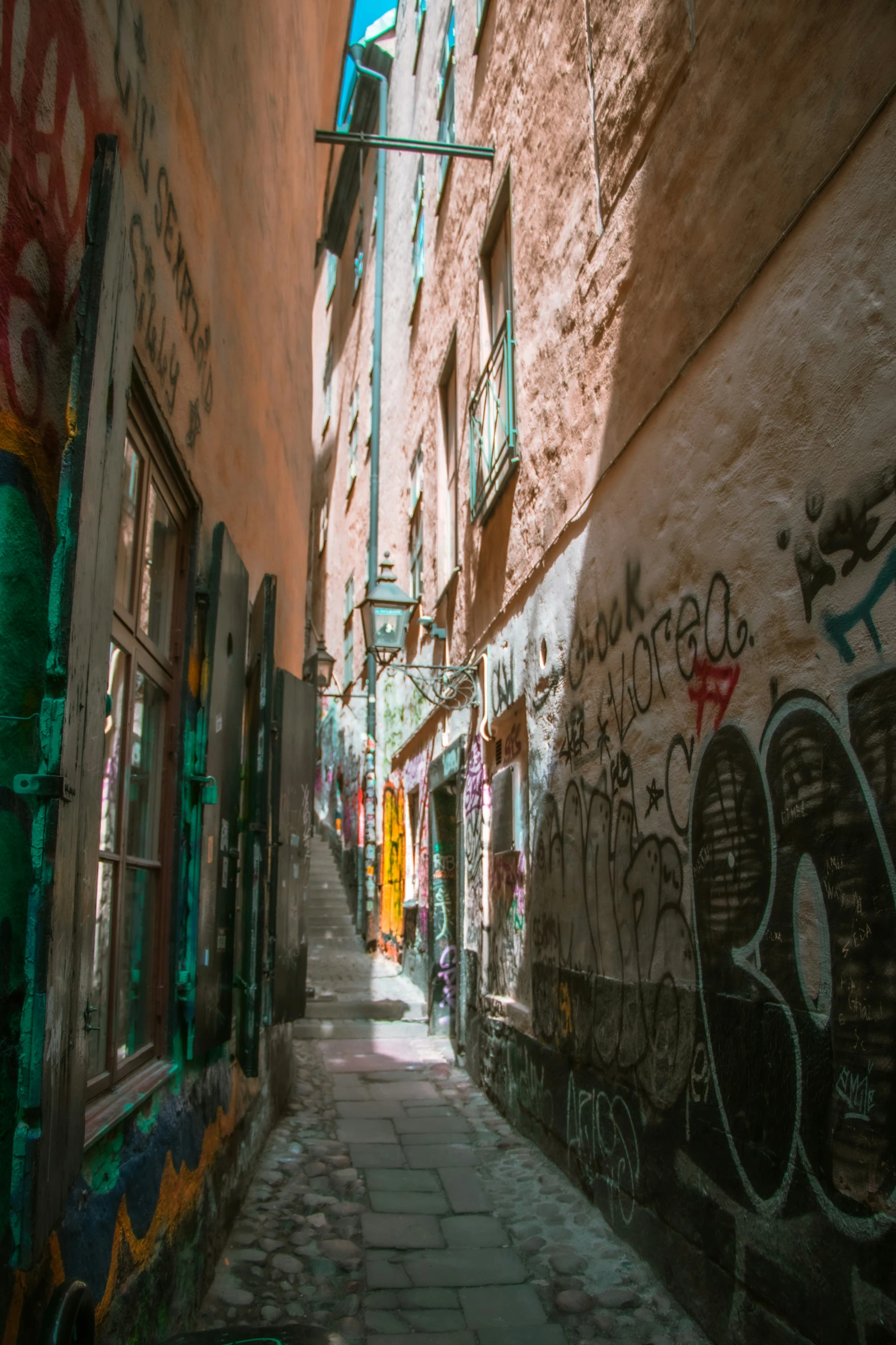 a narrow, stone alleyway with grafitti on the buildings