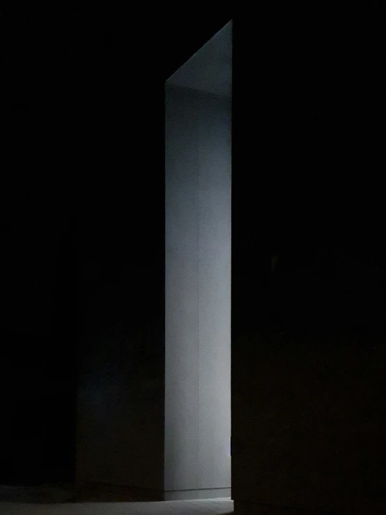 the dark room with an illuminated pillar is dimly lit