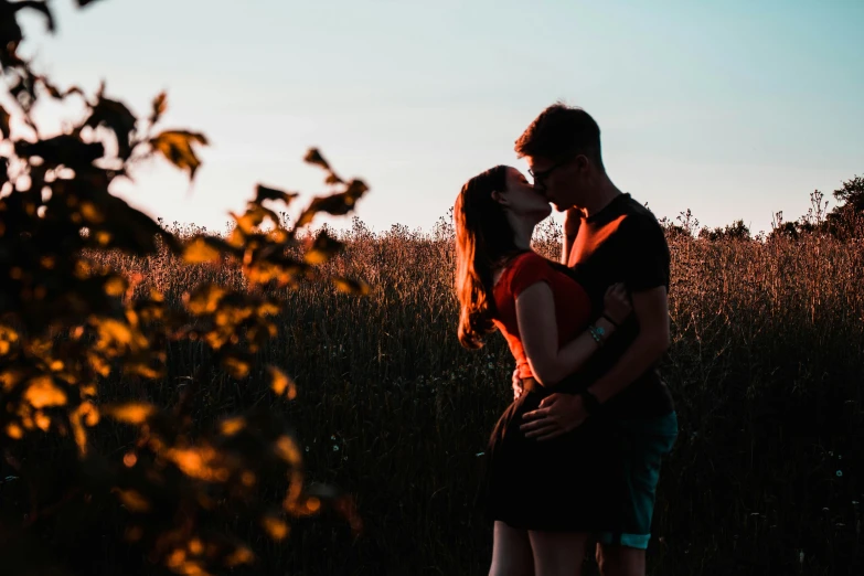 a couple emcing in the grass with trees behind them