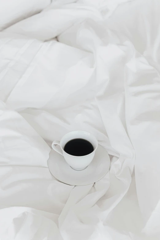 a cup of coffee sitting on top of a white cloth