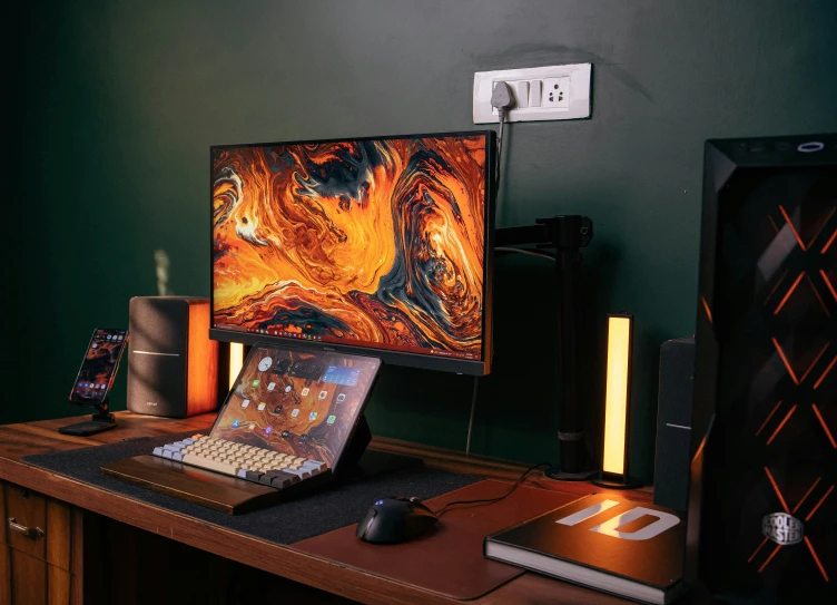 laptop computer on an open desk in front of the large monitor