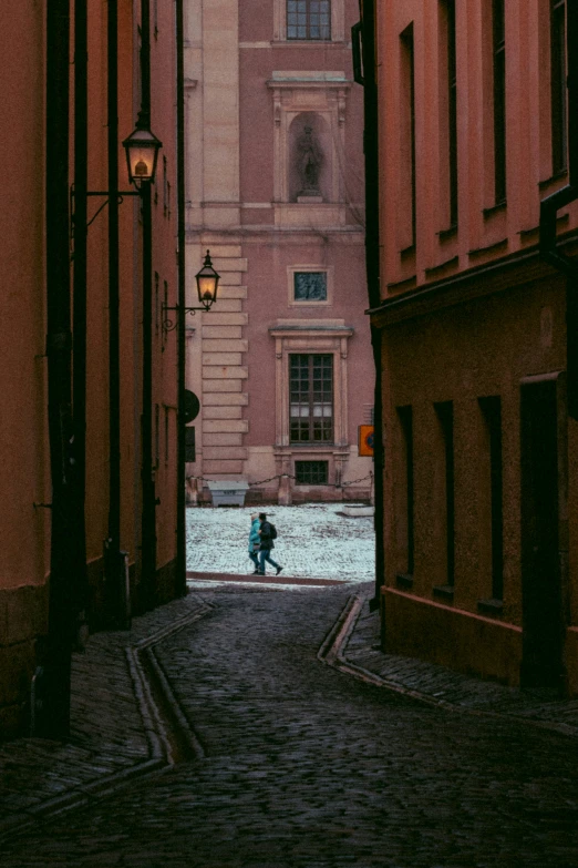 a person standing at an alleyway that runs between two buildings