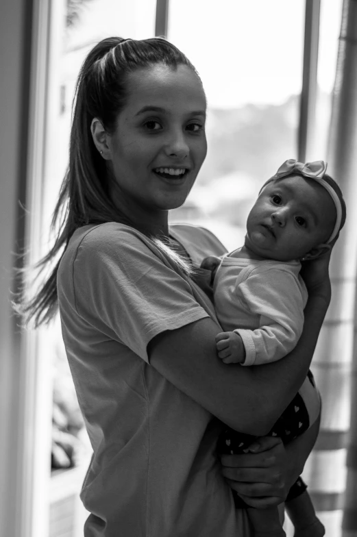 a woman holds her baby in front of a window