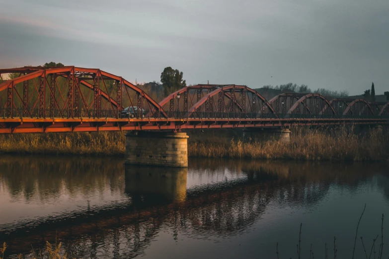 a bridge spanning the width of a lake with a truck on it