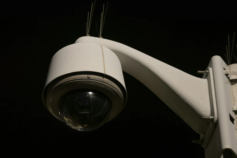 closeup of security camera on top of a white pole