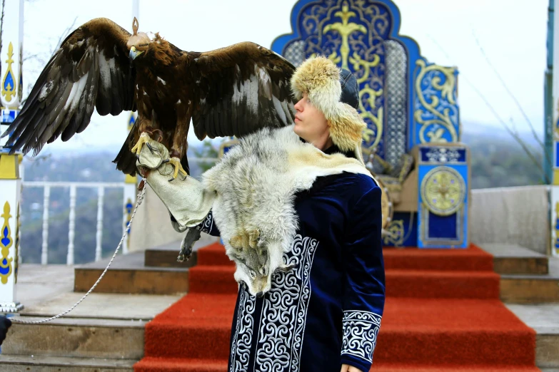 a woman holding a large bird while standing on top of a stage