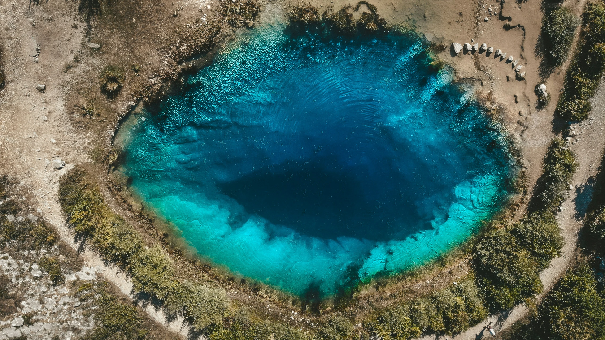 a blue lake surrounded by green trees and water