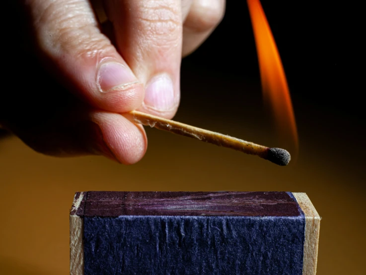 a hand holding a cigarette over top of an open box