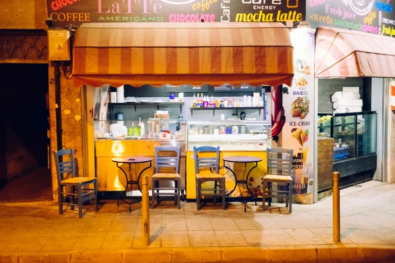 yellow awning above tables and chairs near a small food cart