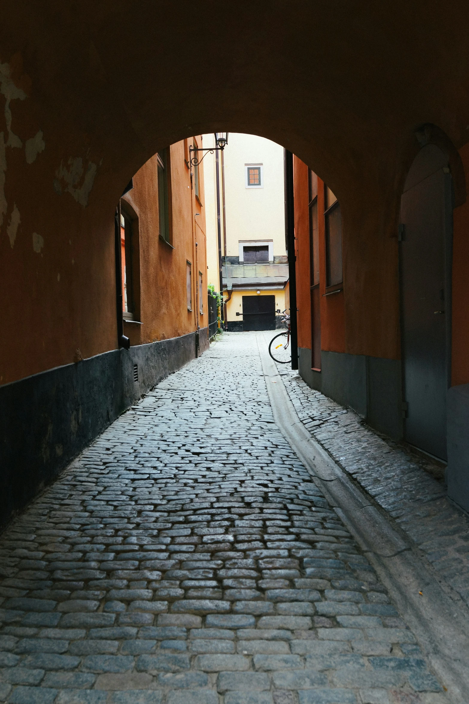 an archway is open to an alley of brick pavement