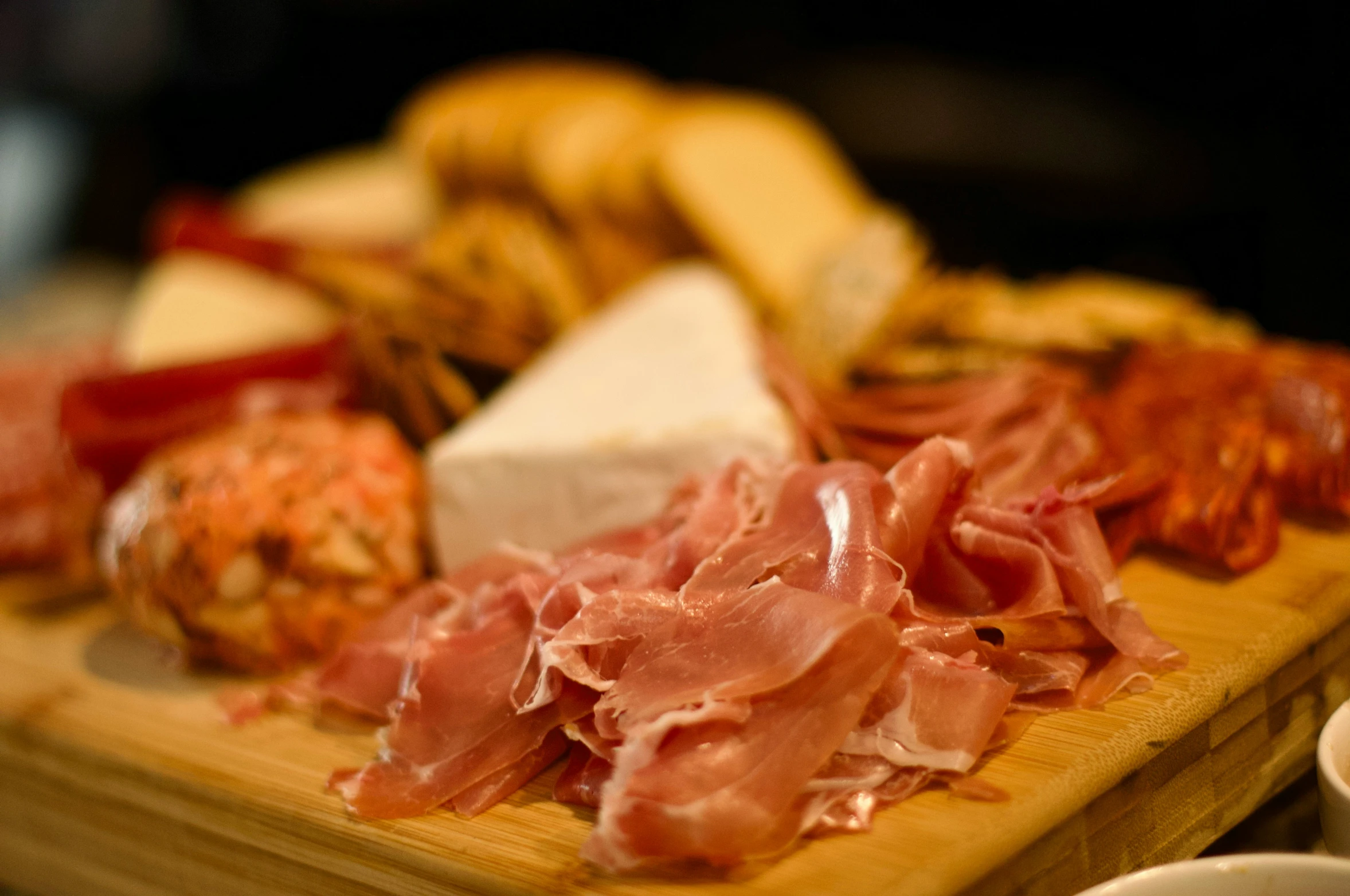 a wooden plate topped with ham and cheese