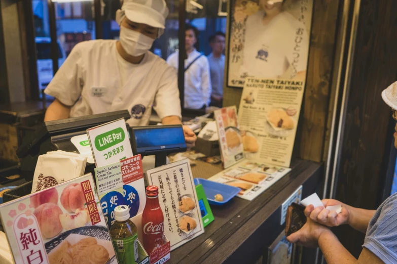 a man in a cap at a sushi restaurant working at his phone