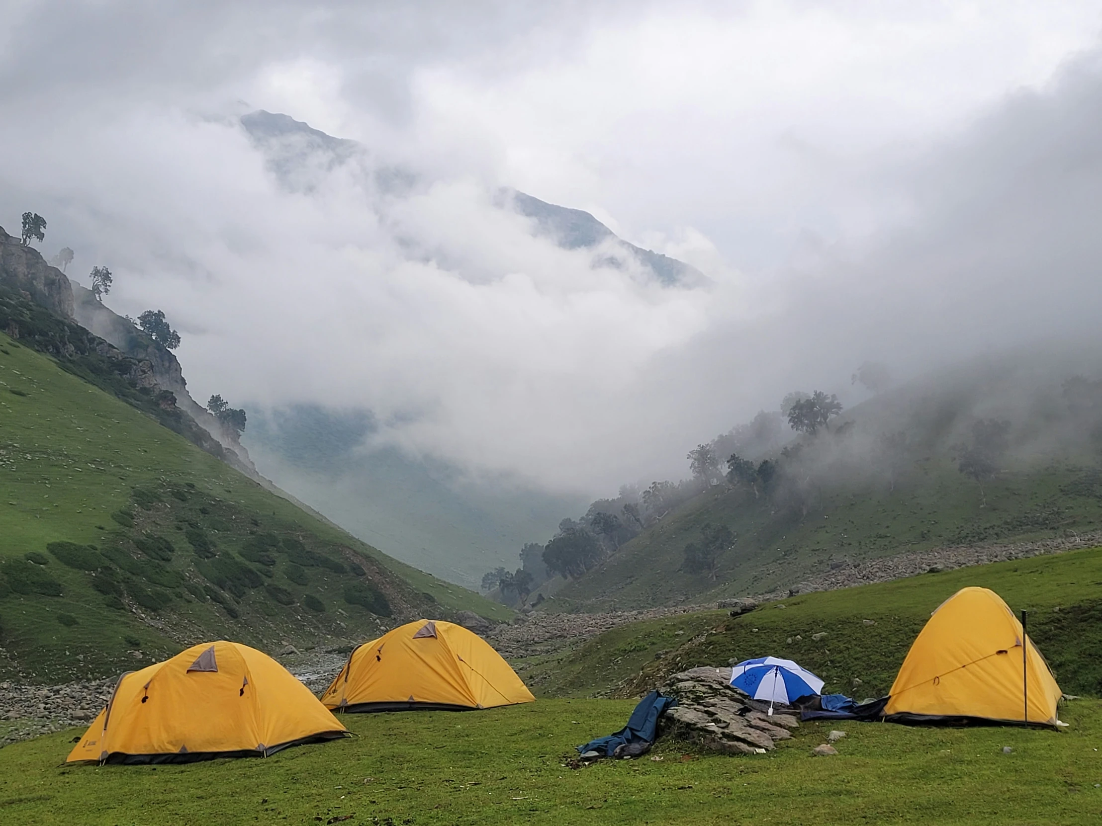 a field with some tents in the middle of mountains