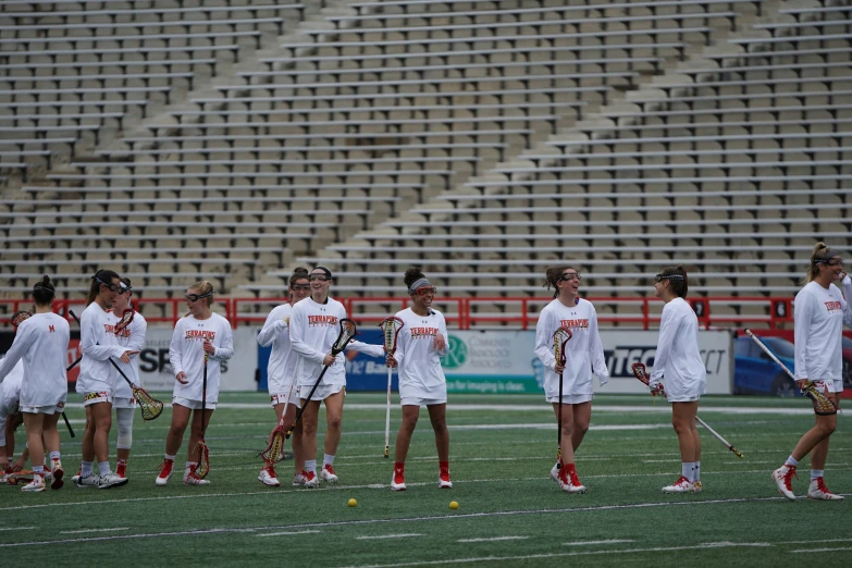 a group of girls lacrosse players gather on the field