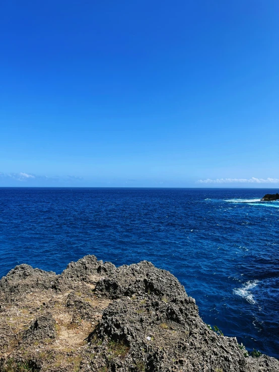 a man sitting on top of a large rock near the ocean