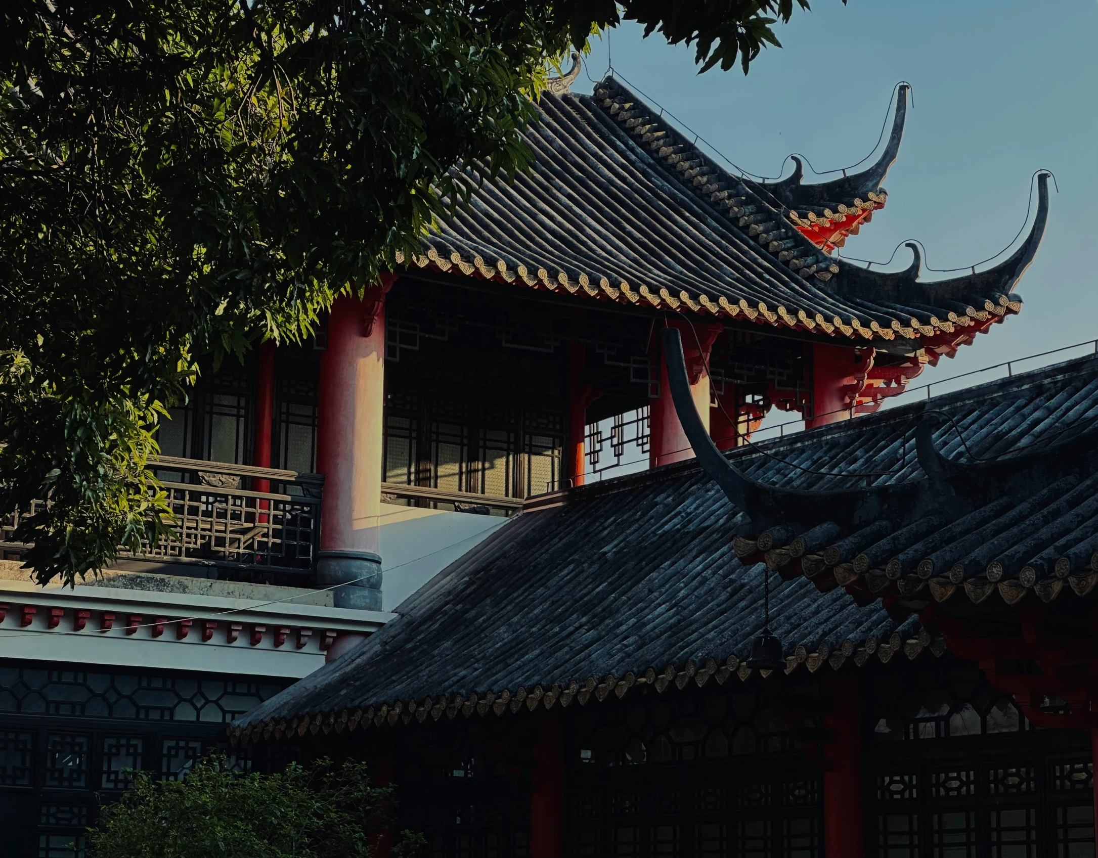 a red pagoda with dragon statues above it and trees