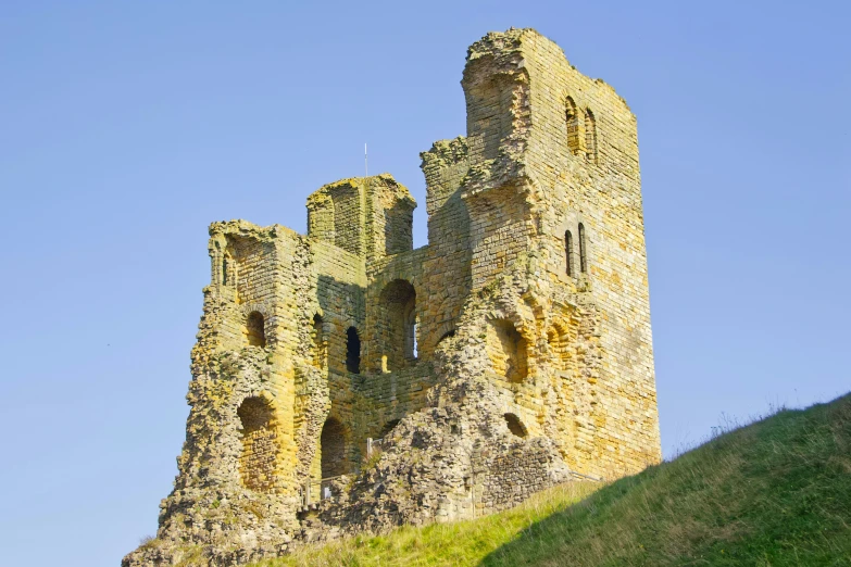 a very tall castle standing above the green hillside