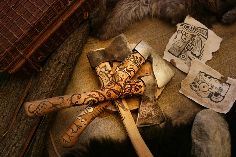 an old axe, wooden spatula, a pair of scissors and some paper with drawings on it