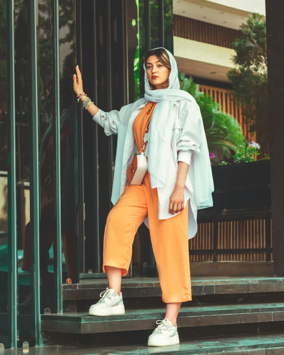 a woman in an orange jumpsuit and blue jacket stands in front of a door