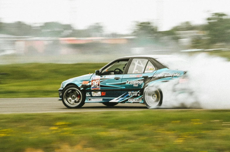 a blue car making a lot of smoke on a track