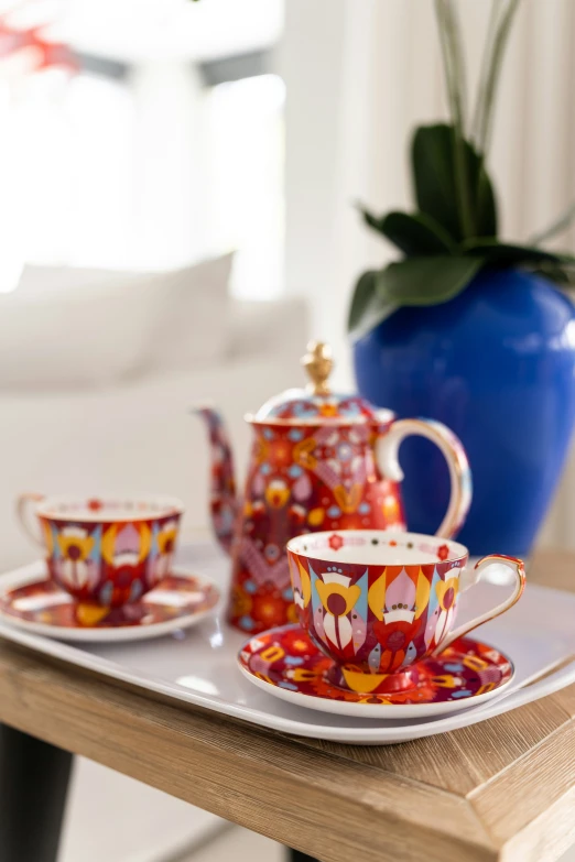 a small tea pot and three cups are on a tray