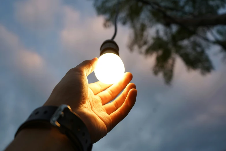 a light bulb is being held up with a hand