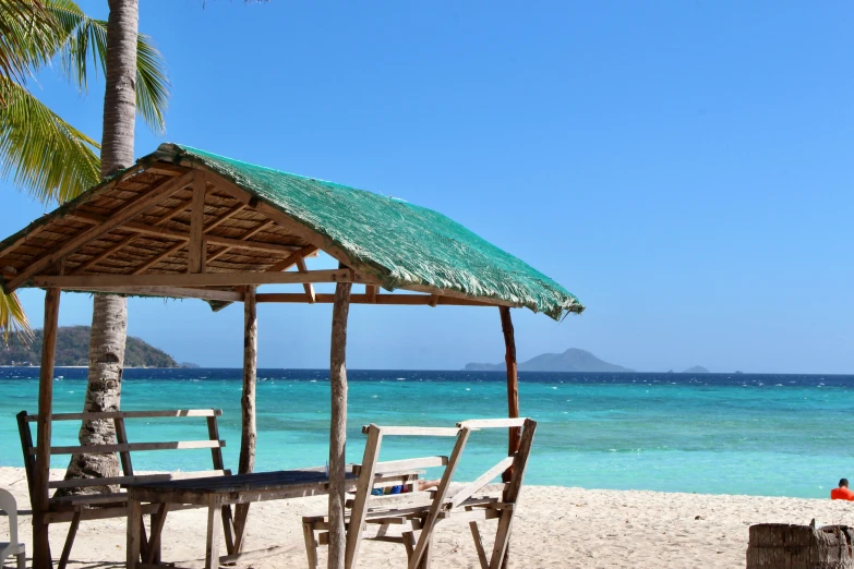 a small hut on the beach with some chairs