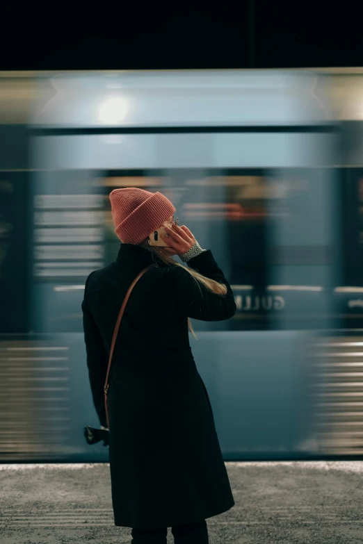 a woman standing in front of a train talking on a phone