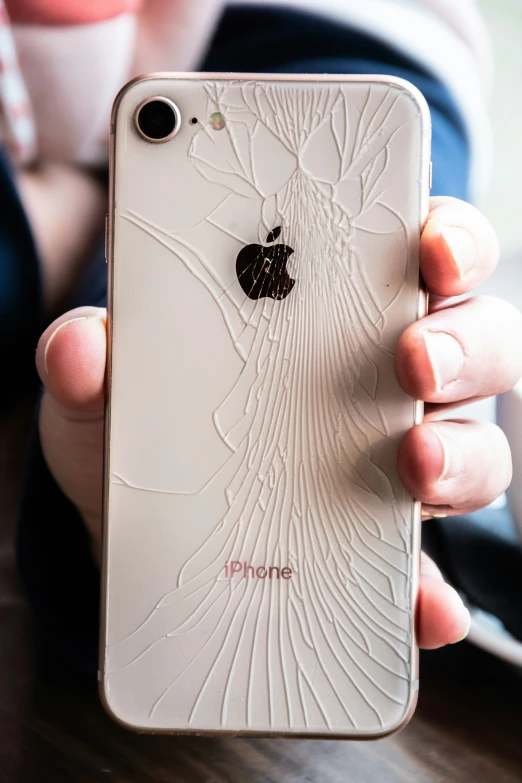 a person holding an iphone with a broken screen