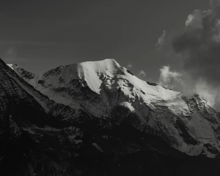 a very tall snowy mountain under a cloudy sky