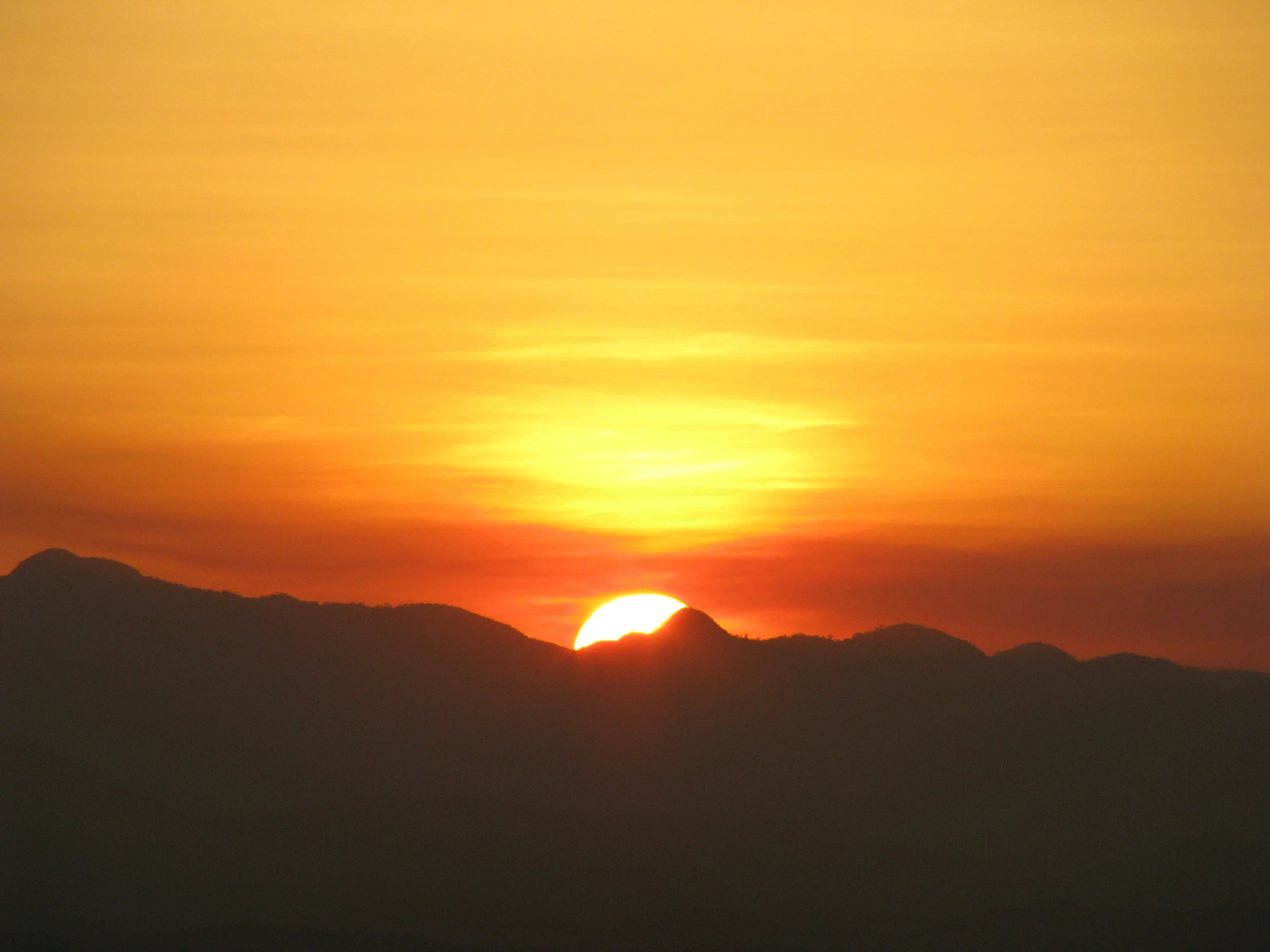 a lone boat floating in the ocean as the sun rises