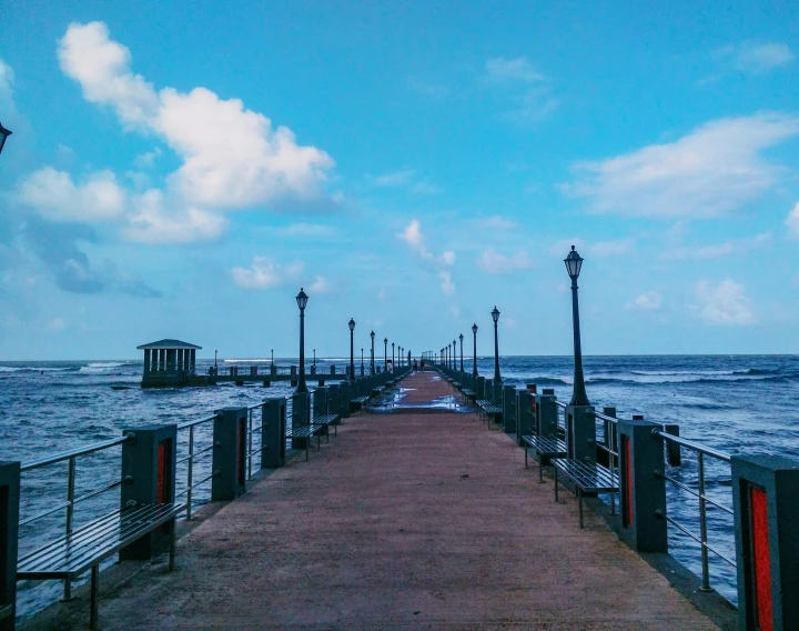 a view of a long pier with the ocean and boats