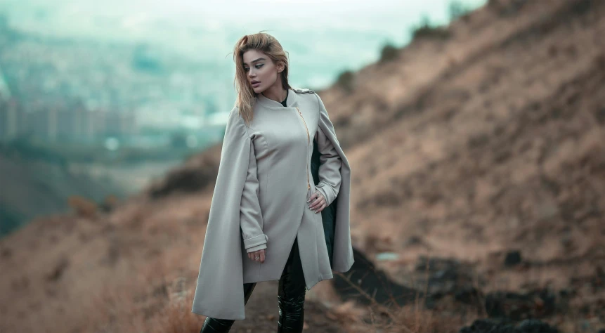 a woman standing in a field wearing a trench coat