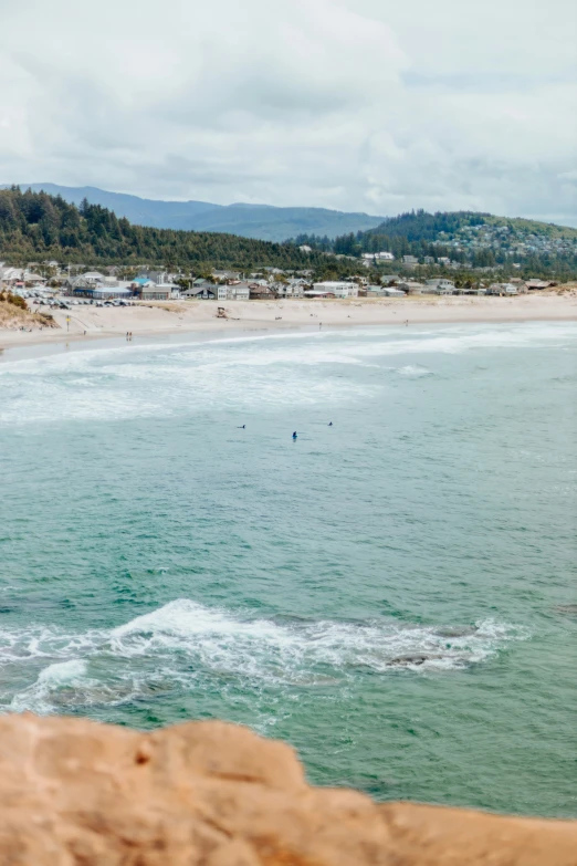 two surfers in the blue ocean and one is walking on the beach