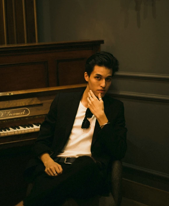 a young man sits at the piano and looks up