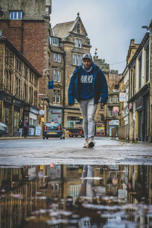 a man wearing sweatpants, blue jacket and sneakers running down the street