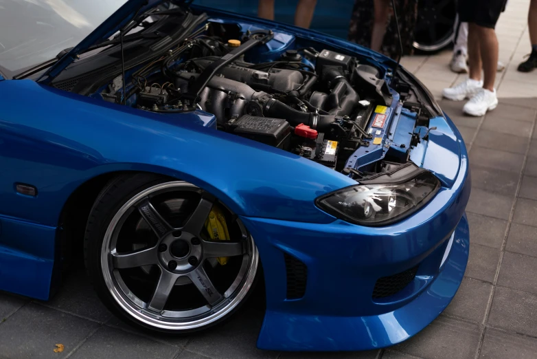 the front end of a blue car showing its hood open