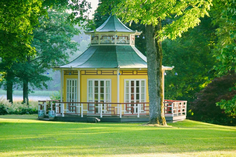 small gazebo on a park with a bench in the grass