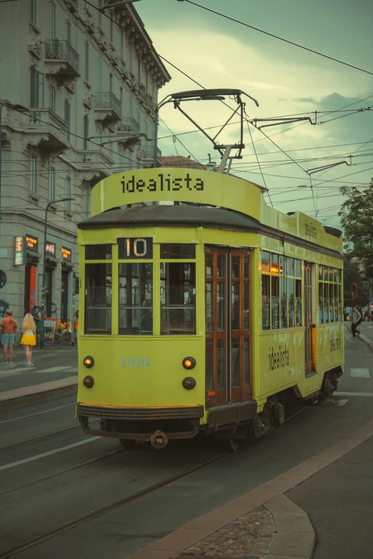 an old style yellow trolley car traveling on a city street