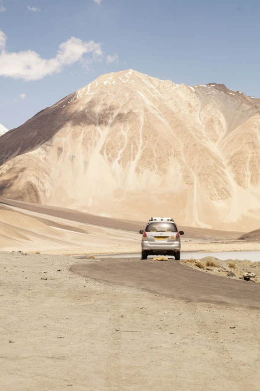 a car is driving through a valley near a mountain