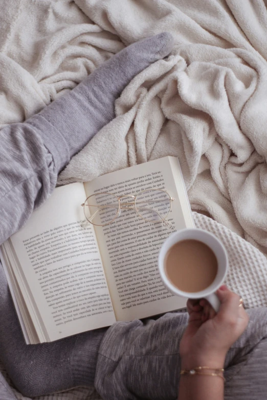 a woman is reading while holding her coffee