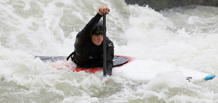 a man riding on top of a paddle board in a river