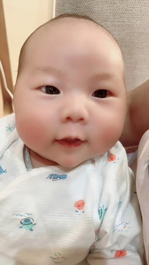 an infant girl smiles for the camera as she holds it up