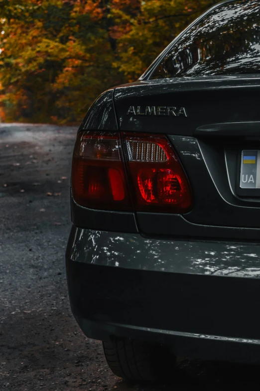 the back end of a black car parked on the side of the road