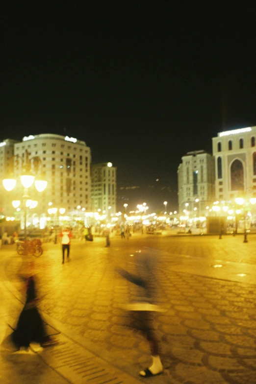 people in the night walking around an outdoor plaza